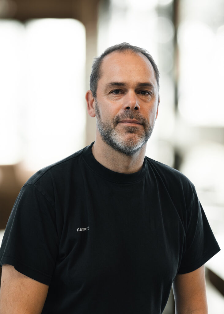 Mand i sort t-shirt, indendørs.