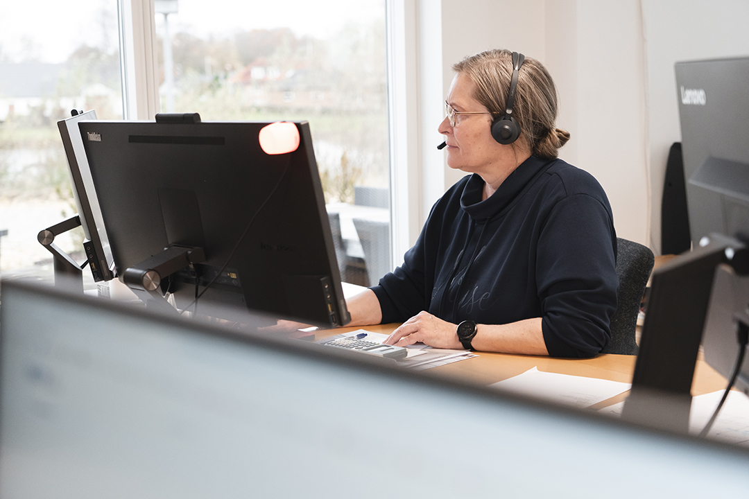 Person arbejder ved computer med headset om bendixen