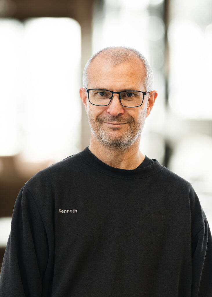 Mand i sort trøje, uskarp baggrund.