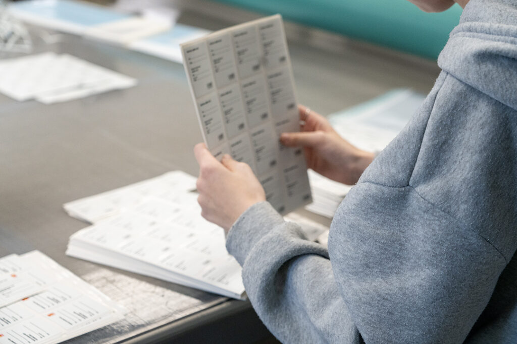 Person sorterer papirark med etiketter og labels