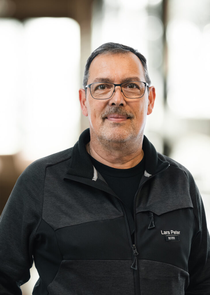 Mand i sort jakke, indendørs.